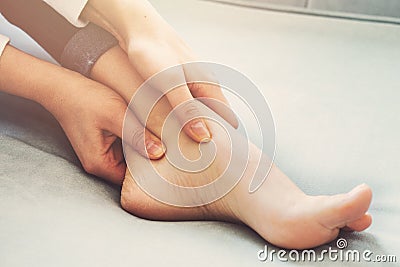 A young woman massaging her painful ankle. Stock Photo
