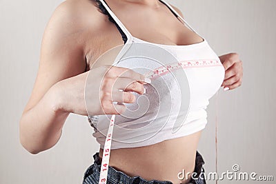 Young woman measures her breasts with a measuring tape Stock Photo