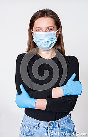 Young woman in medical mask and gloves standing with arms crossed on her chest, white background Stock Photo