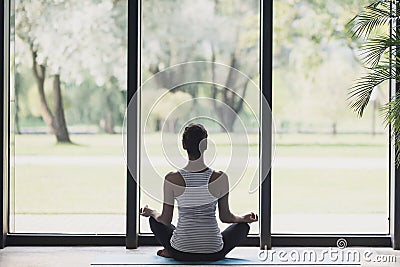 Young woman meditate at home, Girl practicing yoga near floor window in yoga studio, Relaxation, body care concept Stock Photo