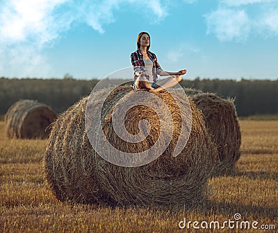 Young woman meditating on haystack Stock Photo