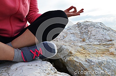 young woman meditation in a yoga pose at the beach. girl in lotus position on an empty stone seashore. takes yoga, sports, Stock Photo