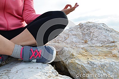 young woman meditation in a yoga pose at the beach. girl in lotus position on an empty stone seashore. takes yoga, sports, Stock Photo