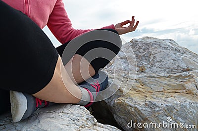 young woman meditation in a yoga pose at the beach. girl in lotus position on an empty stone seashore. takes yoga, sports, Stock Photo