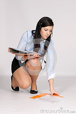 Young woman in mini skirt and blouse squatting rises from the ground 