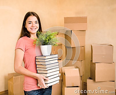 Young woman moving house to college, holding pile books and plan Stock Photo