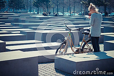 Young woman next to rented bicycles looking at the map at the holocaust memorial, Berlin, Germany Editorial Stock Photo