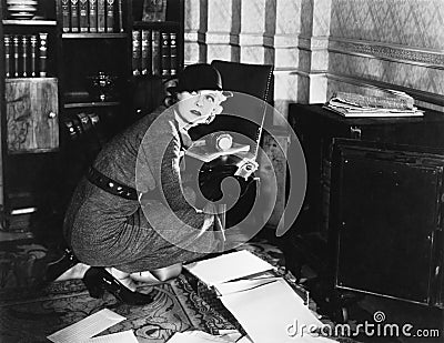 Young woman in an office next to a safe, looking over her shoulder Stock Photo