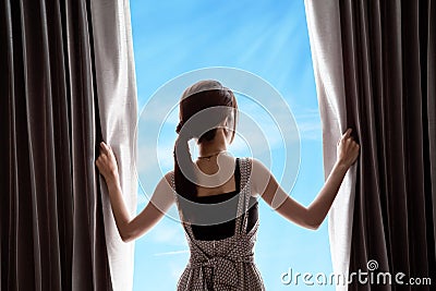 Young woman opening curtains and blue sky Stock Photo