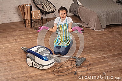 Young woman opening vacuum cleaner, possible failure. Houseworking in home. Stock Photo