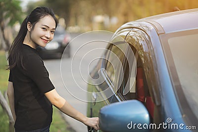 Young woman opens door of blue metallic car Stock Photo