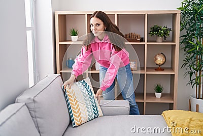 Young woman organizing sofa standing at home Stock Photo