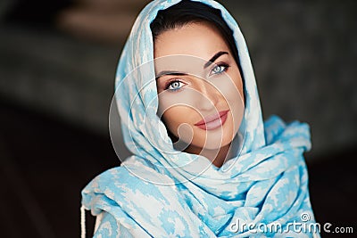 Young woman of oriental appearance in a blue scarf. Beauty portrait of arabian or indian girl with perfect makeup Stock Photo