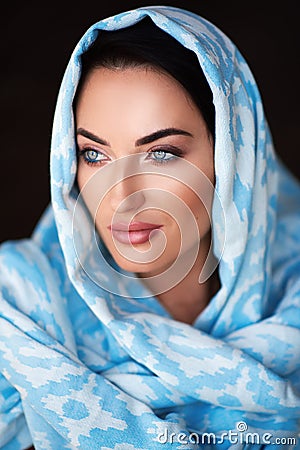 Young woman of oriental appearance in a blue scarf. Beauty portrait of arabian or indian girl with perfect makeup Stock Photo