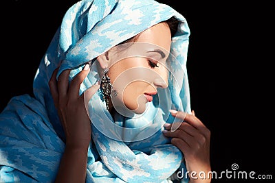 Young woman of oriental appearance in a blue scarf. Beauty portrait of arabian or indian girl with perfect makeup Stock Photo