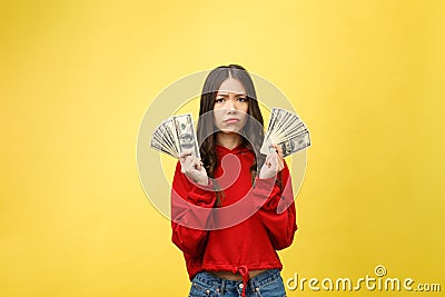 Young woman over yellow wall holding dollars stressed with hand on head, shocked with shame and surprise face, angry and Stock Photo