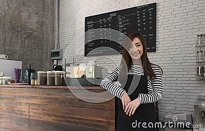 Young woman owner of a cafe stand in front of coffee counter, yo Stock Photo