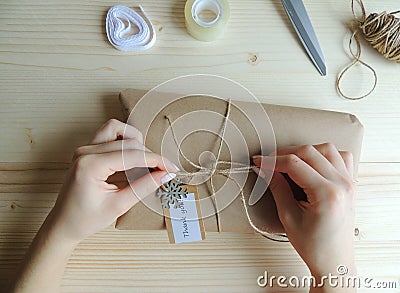 Young woman, owner of sewing small business wrapping an parcel for delivery. Gift wraping idea. Stock Photo