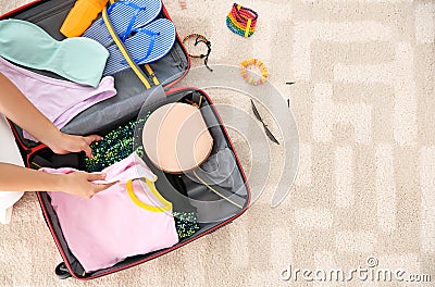 Young woman packing suitcase for summer journey at home Stock Photo