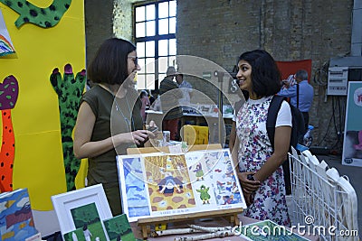 Young woman painter left presenting her paintings to another girl Editorial Stock Photo