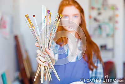 Young woman painter showing dirty paintbrushes in artist workshop Stock Photo