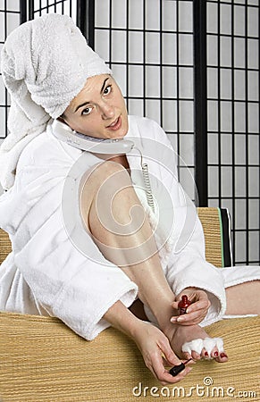 Young woman painting her nails while on the phone Stock Photo