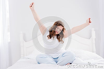 young woman in pajama stretching in morning on bed Stock Photo