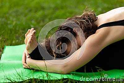 Young woman in park practicing yoga. Paschimottanasana Pose Stock Photo