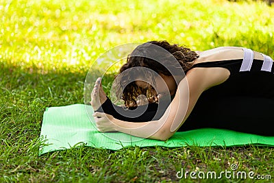 Young woman in park practicing yoga. Paschimottanasana Pose Stock Photo