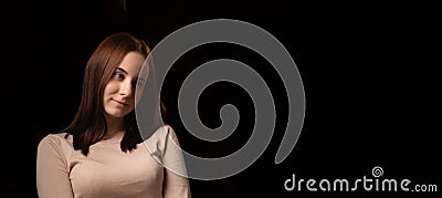 Young woman pensive. Looking away. Dark background. Girl with brown hair in a sweater. Reflections, thoughts. Banner, place for Stock Photo