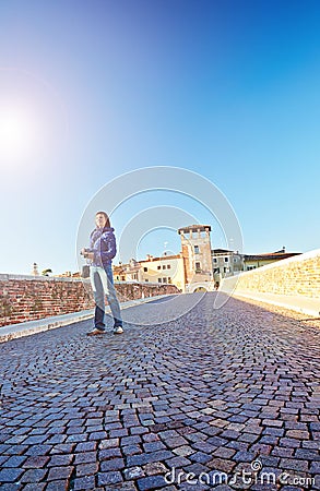 Young woman photographer beams morning sun bridge Ponto Pietra castel Vecchio river Adige Italy Verona Stock Photo