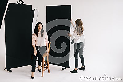 Young woman photographer is preparing backdrop in studio for photo shoot. Stock Photo