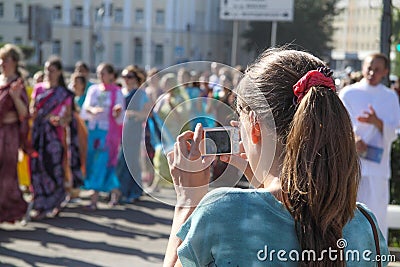 Young woman photographing a group of hare Krishna Editorial Stock Photo