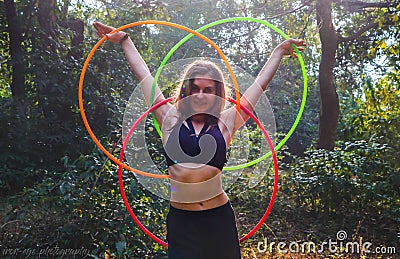 a beautiful woman standing next to some colorful hoops in the woods Stock Photo