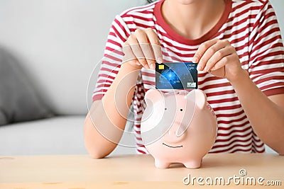 Young woman with piggy bank and credit card at home, closeup Stock Photo