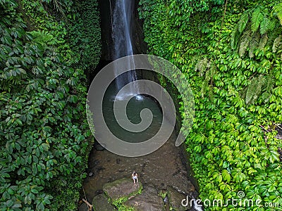 A young woman in a pink dress at Leke Leke waterfall in a lush tropical forest, Bali Editorial Stock Photo