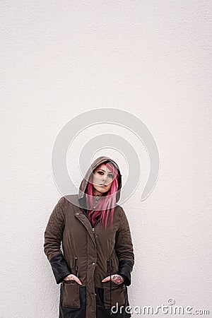 young woman with pink hair piercings and tattoos against wall with copy space Stock Photo