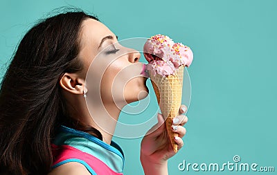 Young woman in pink hat eat strawberry ice-cream dessert in waffle cone on modern light blue Stock Photo