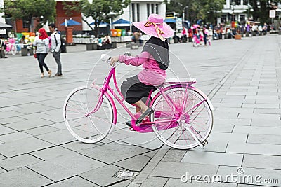 Young woman in pink hat riding a bicycle in city. Active people. Outdoors Editorial Stock Photo