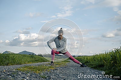 Young woman in pink leggings stretching and warming up before going for a run Stock Photo