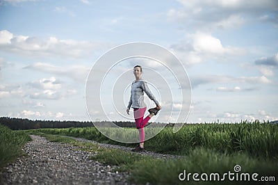 Young woman in pink leggings stretching and warming up before going for a run Stock Photo