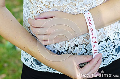 Young woman placing a white bracelet with motivational message stating: I can and I will Stock Photo