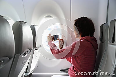 Young woman in plane taking photo Stock Photo