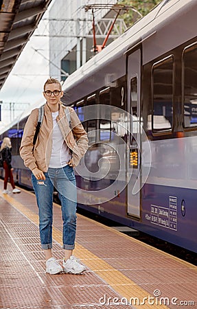 Young woman on the platform waiting for the train. Beautiful girl at the train station. Travel by train. Railway station in Stock Photo