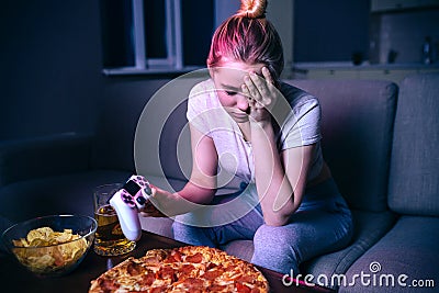 Young woman playing game at night. Upset unhappy model look down. Loose game. Hold gamepad in hand. Watching streaming Stock Photo