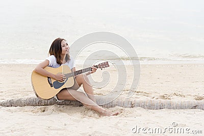 Young woman playing guitar on the beach. Musician lifestyle. Travel concept Stock Photo