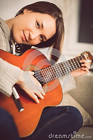 Young woman playing guitar at home. Relaxed happy young woman with music instrument portrait Stock Photo