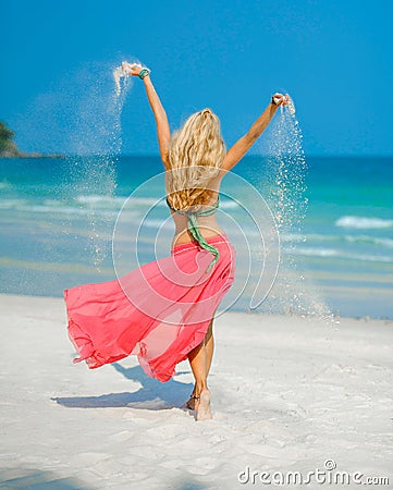 A young woman playing with sand as she dances Stock Photo