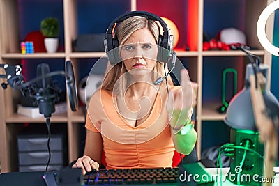 Young woman playing video games showing middle finger, impolite and rude fuck off expression Stock Photo