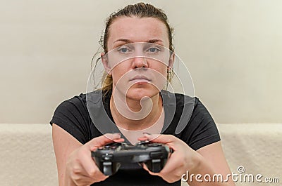 A young woman plays a game console with a joystick Stock Photo